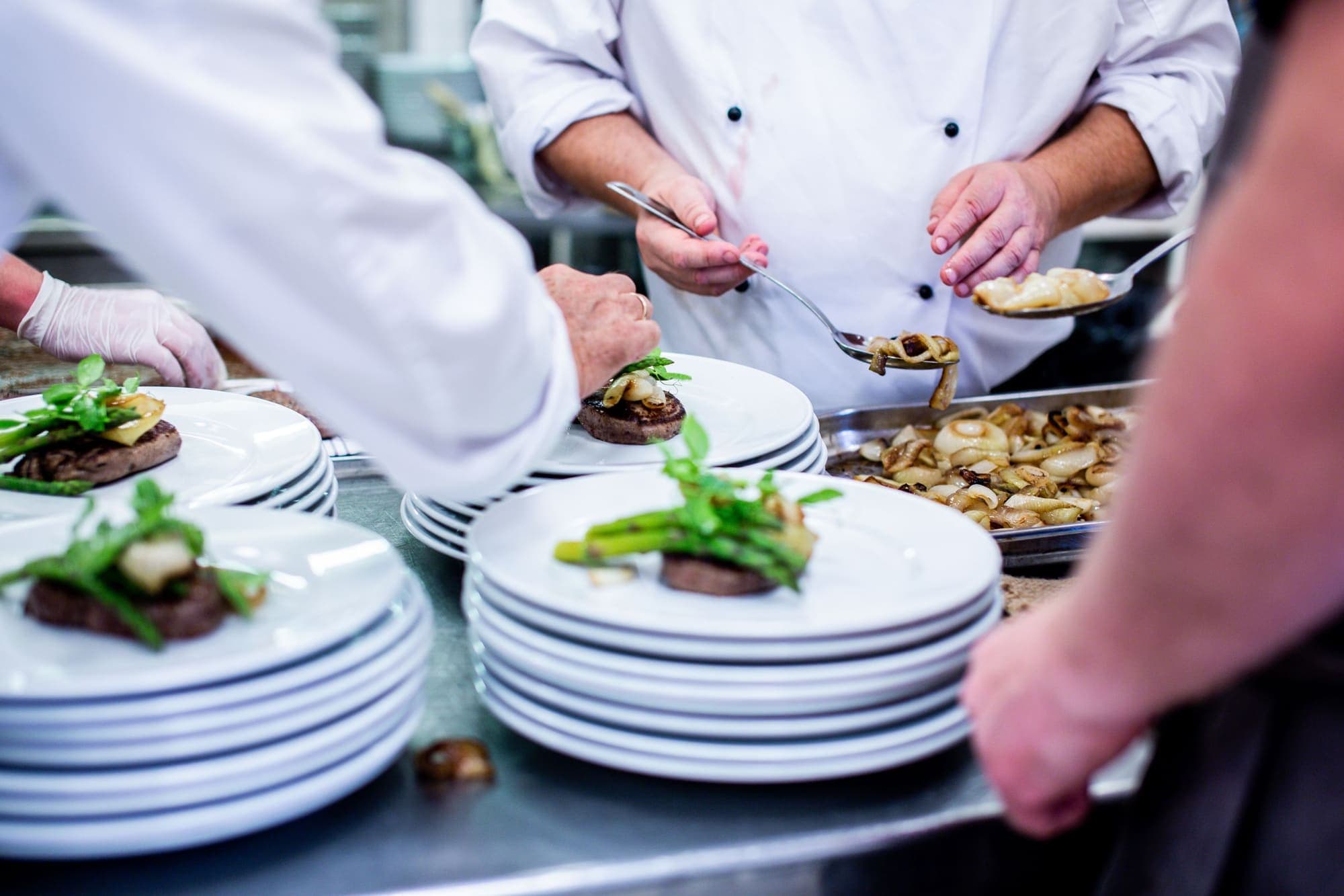 Chefs plating dishes at a busy kitchen pass